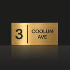 Brushed gold house number and street name sign with a brushed metal look, The Coolum, reading 3 Coolum Ave in black lettering, with a dividing line.