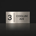 Brushed silver house number and street name sign with a brushed metal look, The Coolum, reading 3 Coolum Ave in black lettering, with a dividing line.