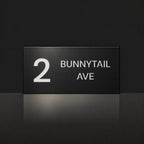 Matte black house number and street name sign, The Maleny, reading 2 Bunnytail Ave in white lettering.