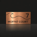 Brushed copper house number and street name sign with a brushed metal look, The Moffat, reading 7 Moffat Court in black lettering, with a wave.