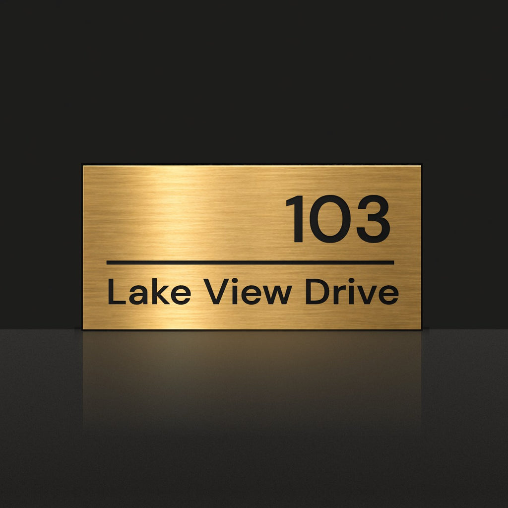 Brushed gold house number and street name sign with a brushed metal look, The Noosa, reading 103 Lake View Drive in black lettering.
