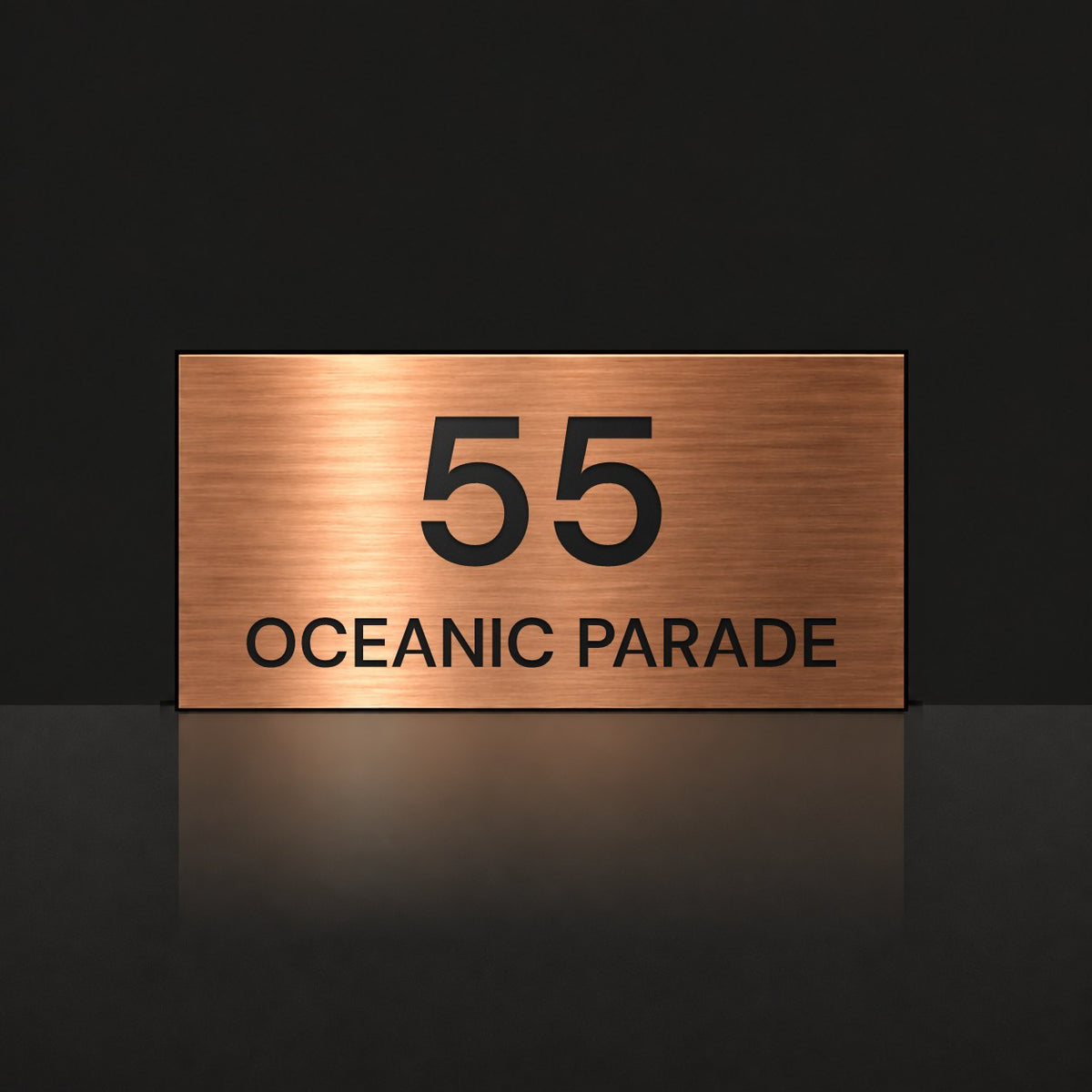 Brushed copper house number and street name sign with a brushed metal look, The Peregian, reading 55 Oceanic Parade in black lettering.