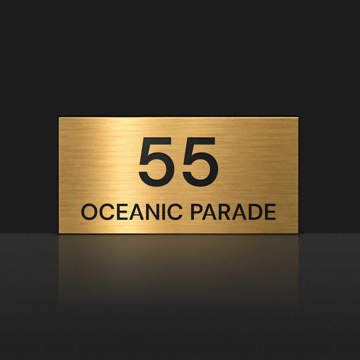 Brushed gold house number and street name sign with a brushed metal look, The Peregian, reading 55 Oceanic Parade in black lettering.