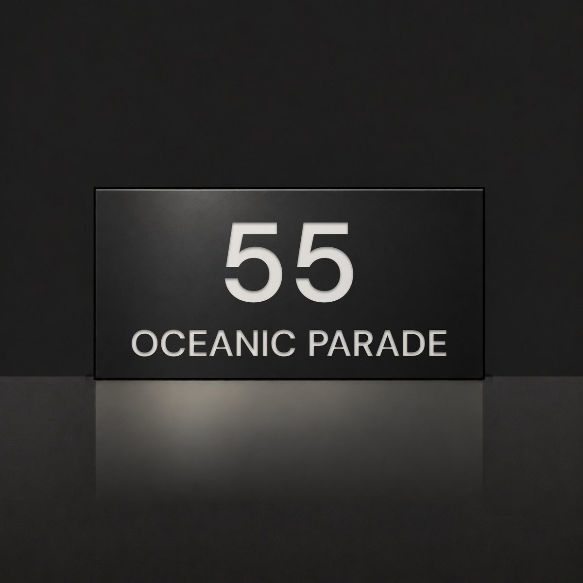 Matte black house number and street name sign, The Peregian, reading 55 Oceanic Parade in white lettering.
