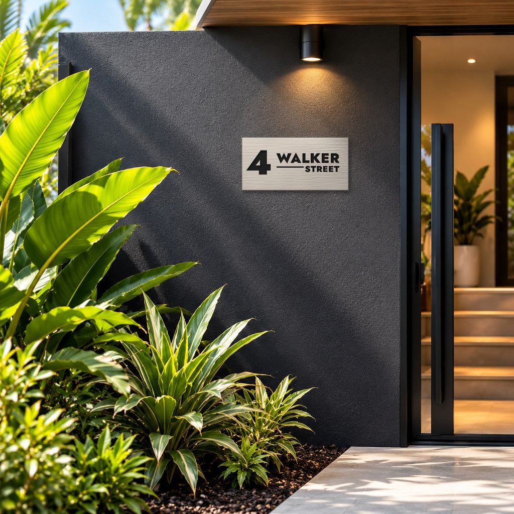 Brushed silver house number and street name sign with a brushed metal look, The Alexandra, reading 4 Walker Street in black lettering, mounted on a charcoal entry wall beside the front door.