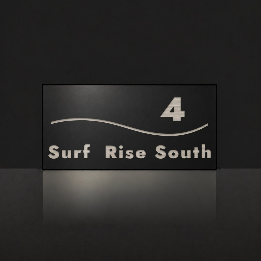 Brushed silver house number and street name sign with a brushed metal look, The Bokarina, black face reading 4 Surf Rise South in silver lettering, with a wave line.
