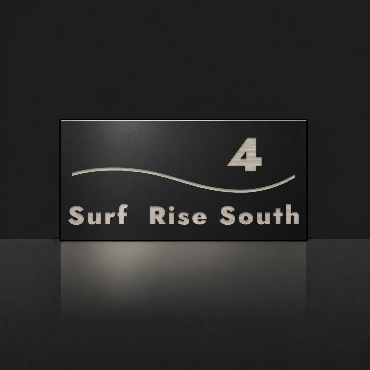 Brushed silver house number and street name sign with a brushed metal look, The Bokarina, black face reading 4 Surf Rise South in silver lettering, with a wave line.