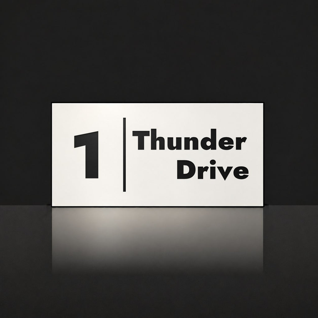 Matte white house number and street name sign, The Coolum, reading 1 Thunder Drive in black lettering, with a dividing line.