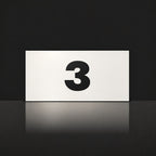 Matte white house number sign, The Kawana, with the number 3 in black lettering.