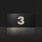 Brushed silver house number sign with a brushed metal look, The Kawana, black face with the number 3 in silver lettering.