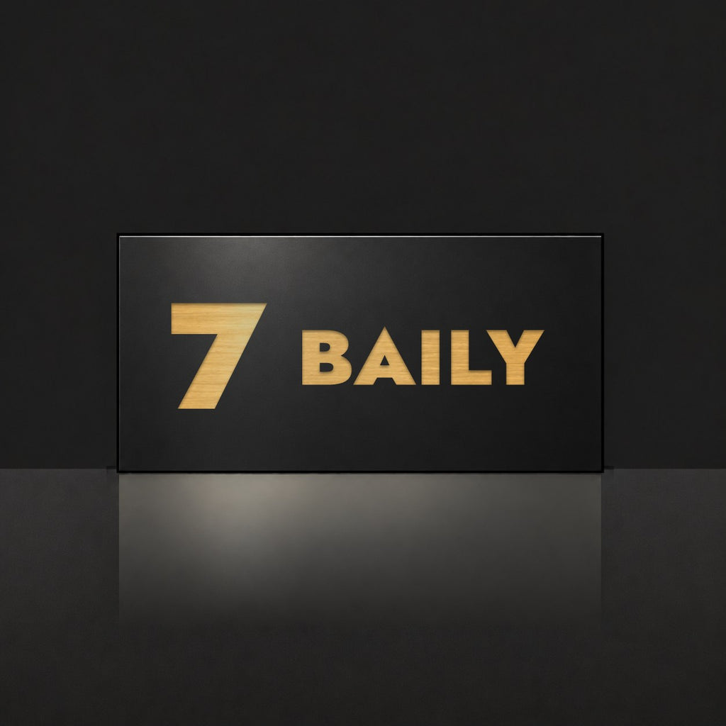 Brushed gold house number and street name sign with a brushed metal look, The Maleny, black face reading 7 Baily in gold lettering.