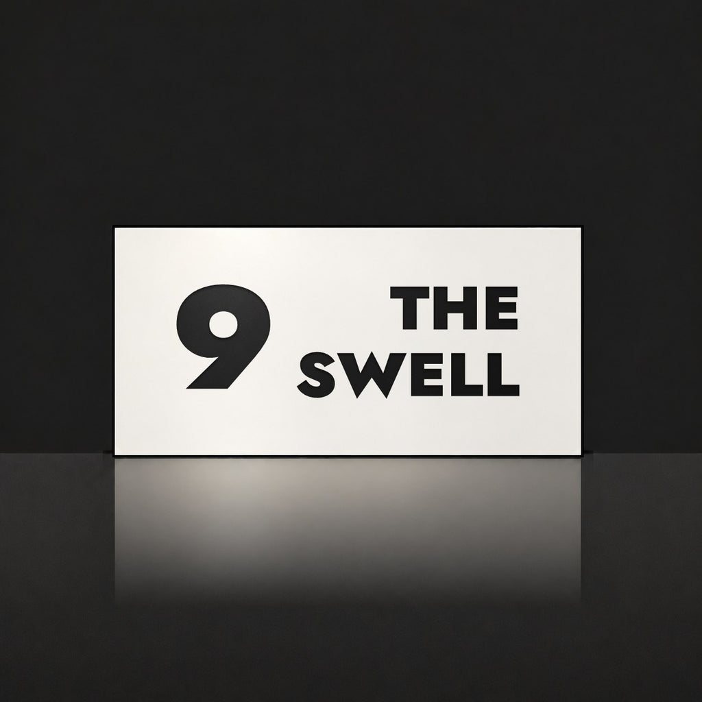 Matte white house number and street name sign, The Marcoola, reading 9 The Swell in black lettering.