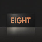 Brushed copper house number sign with a brushed metal look, The Montville, black face with the number spelled out as eight in copper lettering.