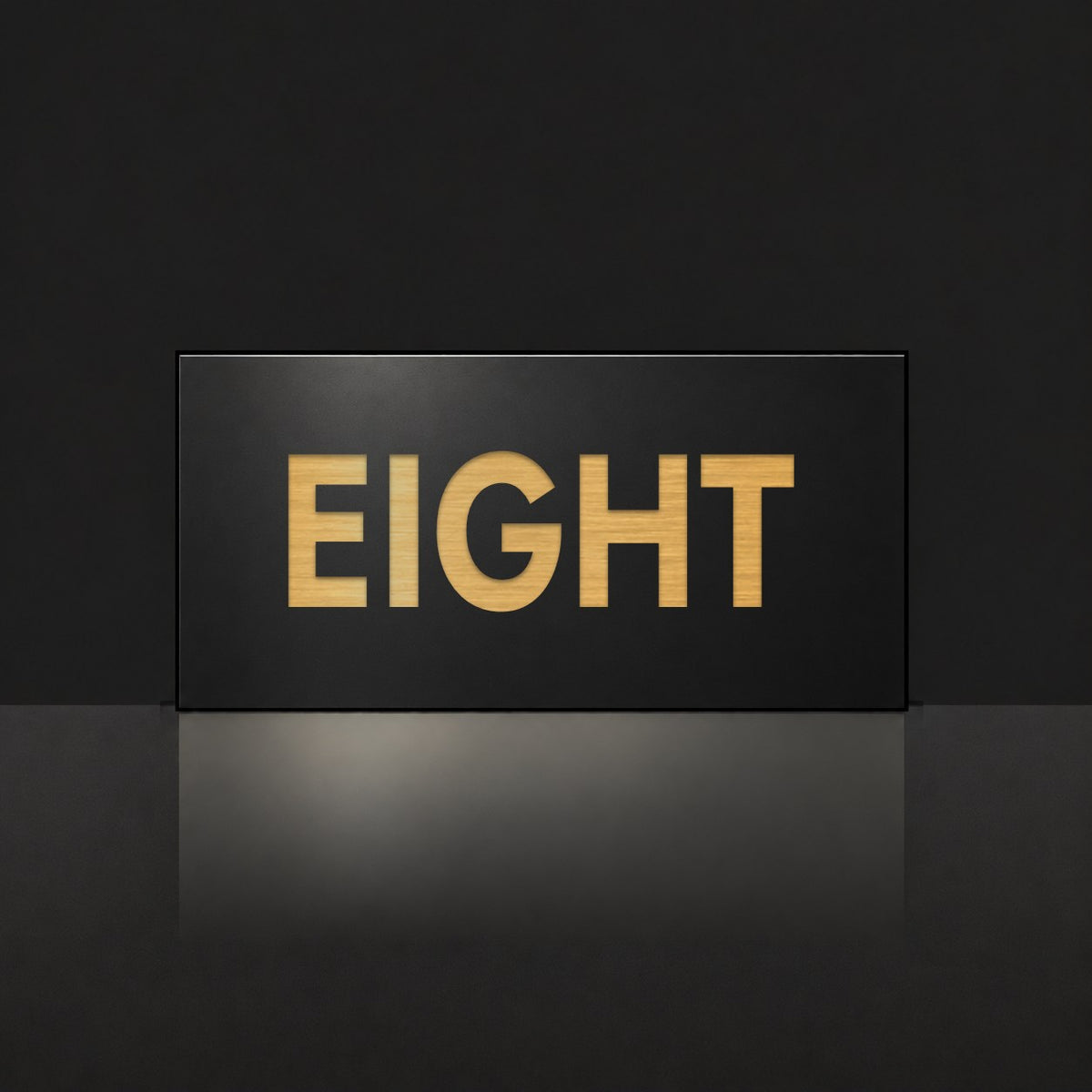 Brushed gold house number sign with a brushed metal look, The Montville, black face with the number spelled out as eight in gold lettering.