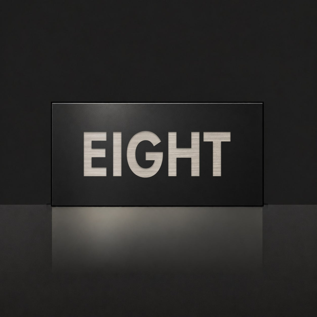 Brushed silver house number sign with a brushed metal look, The Montville, black face with the number spelled out as eight in silver lettering.