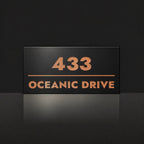 Brushed copper house number and street name sign with a brushed metal look, The Noosa, black face reading 433 Oceanic Drive in copper lettering.