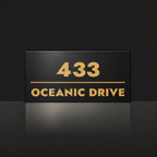 Brushed gold house number and street name sign with a brushed metal look, The Noosa, black face reading 433 Oceanic Drive in gold lettering.