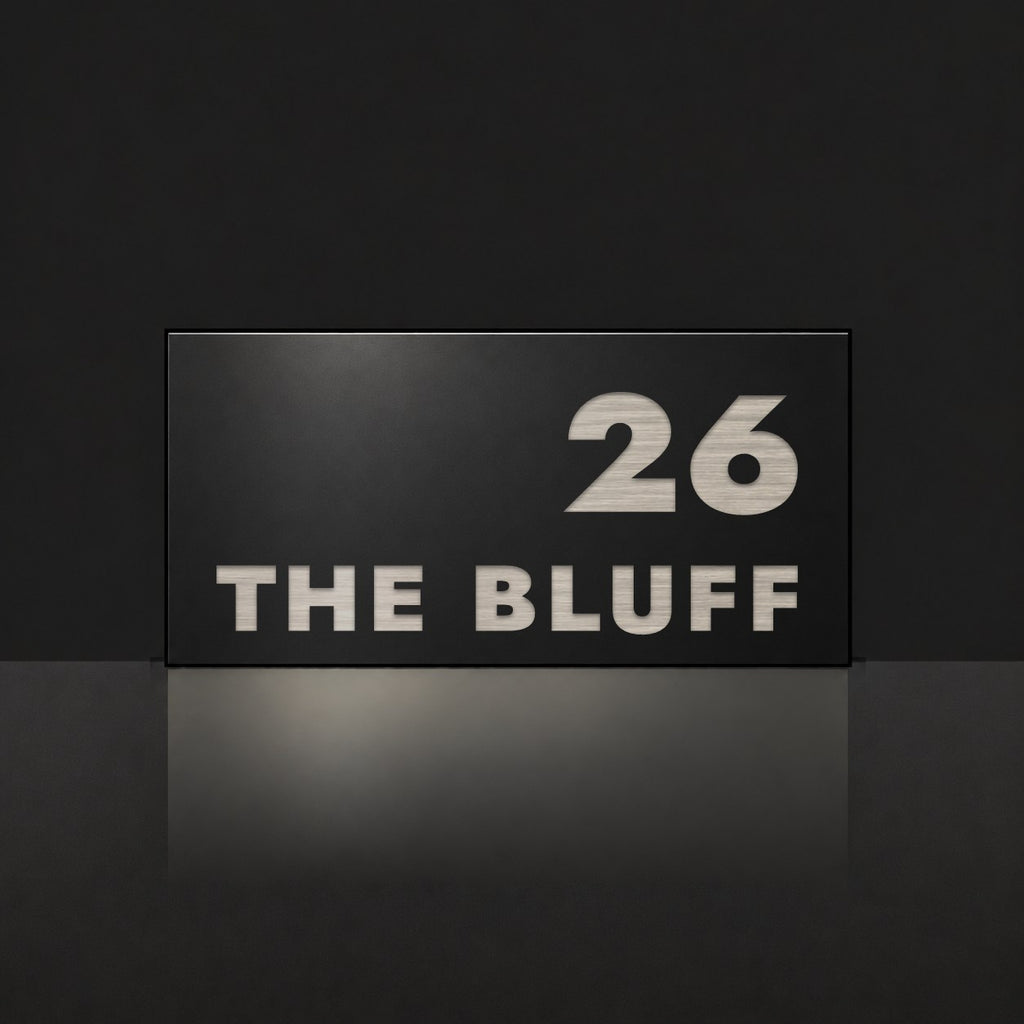 Brushed silver house number and street name sign with a brushed metal look, The Peregian, black face reading 26 The Bluff in silver lettering.