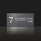 Matte charcoal house number and street name sign, The Alexandra, reading 7 Hamilton Dr in white lettering.