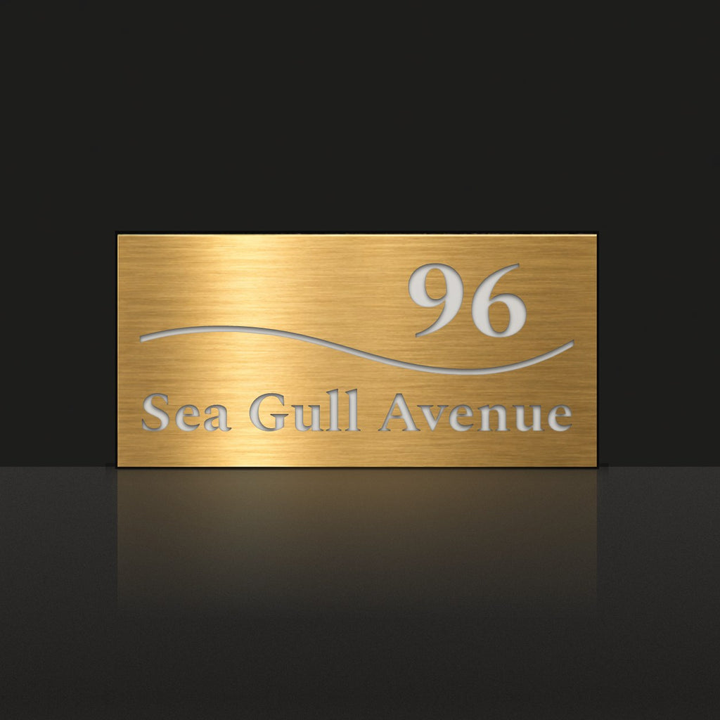 Brushed gold house number and street name sign with a brushed metal look, The Bokarina, reading 96 Sea Gull Avenue in white lettering, with a wave line.