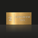 Brushed gold house number and street name sign with a brushed metal look, The Coolum, reading 2 Gingham Ave in white lettering, with a dividing line.
