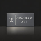 Matte charcoal house number and street name sign, The Coolum, reading 2 Gingham Ave in white lettering, with a dividing line.