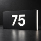 Matte black illuminated house number sign, The Kawana, displaying 75 in glowing white on a dark background.