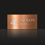 Brushed copper house number and street name sign with a brushed metal look, The Marcoola, reading 4 Nicklin Way in white lettering.