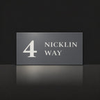 Matte charcoal house number and street name sign, The Marcoola, reading 4 Nicklin Way in white lettering.
