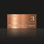 Brushed copper house number and street name sign with a brushed metal look, The Moffat, reading 3 Bungalow Court in white lettering, with a wave.