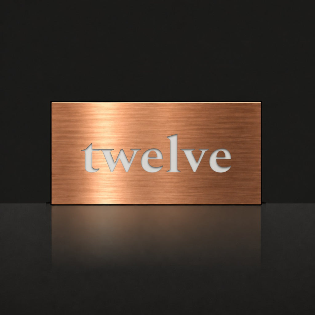 Brushed copper house number sign with a brushed metal look, The Montville, with the number spelled out as twelve in white lettering.