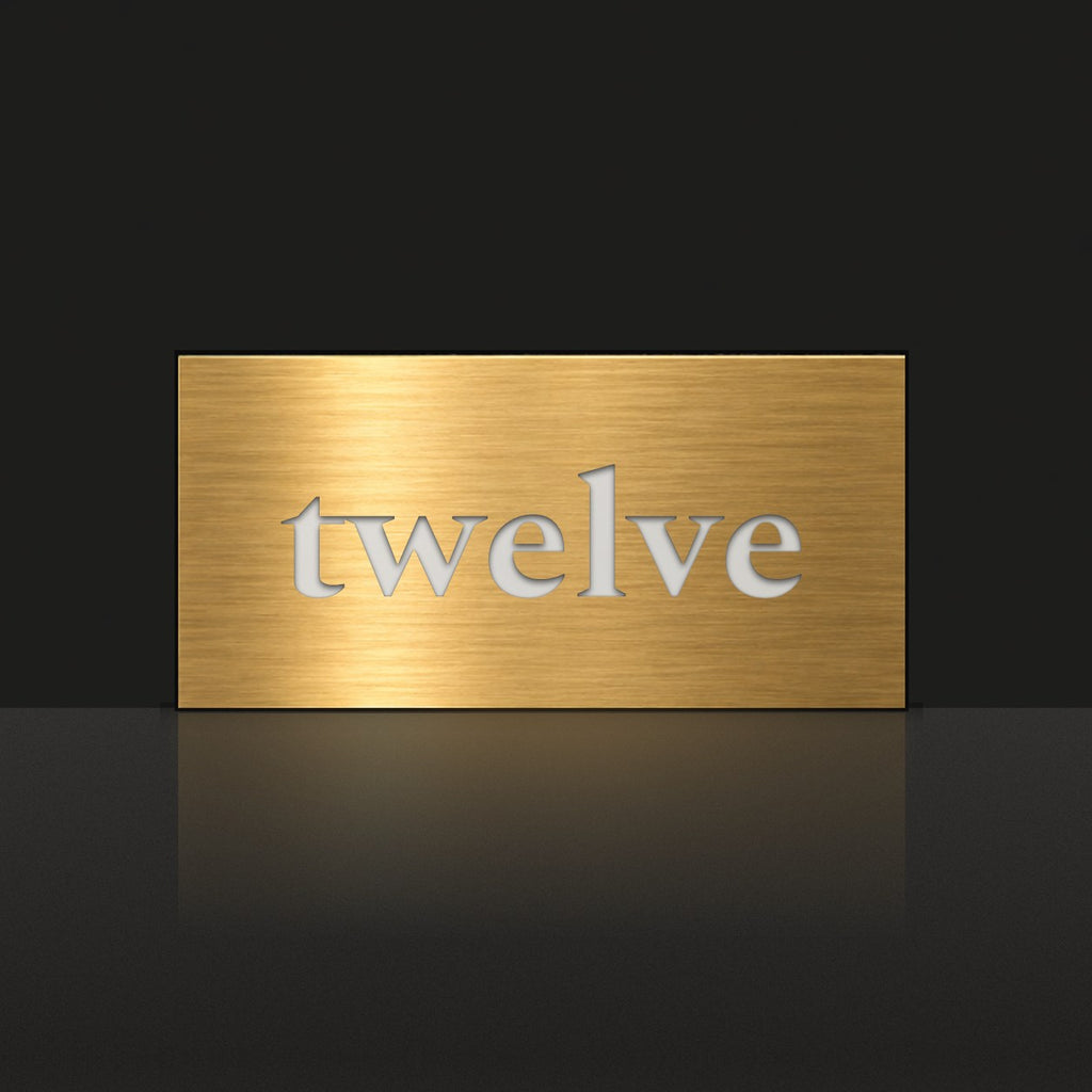 Brushed gold house number sign with a brushed metal look, The Montville, with the number spelled out as twelve in white lettering.