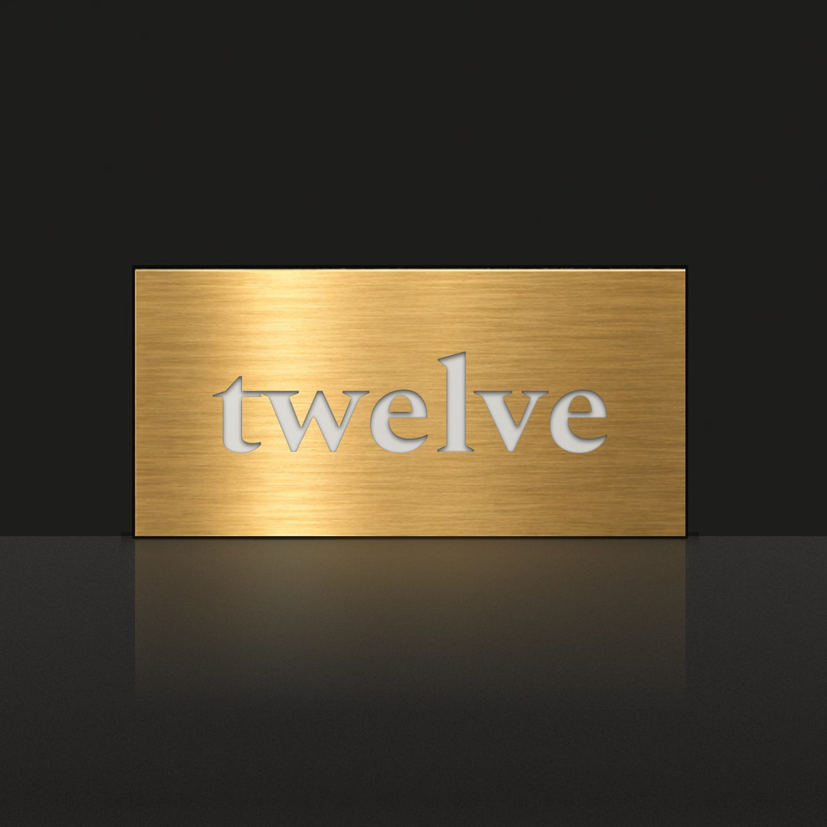 Brushed gold house number sign with a brushed metal look, The Montville, with the number spelled out as twelve in white lettering.