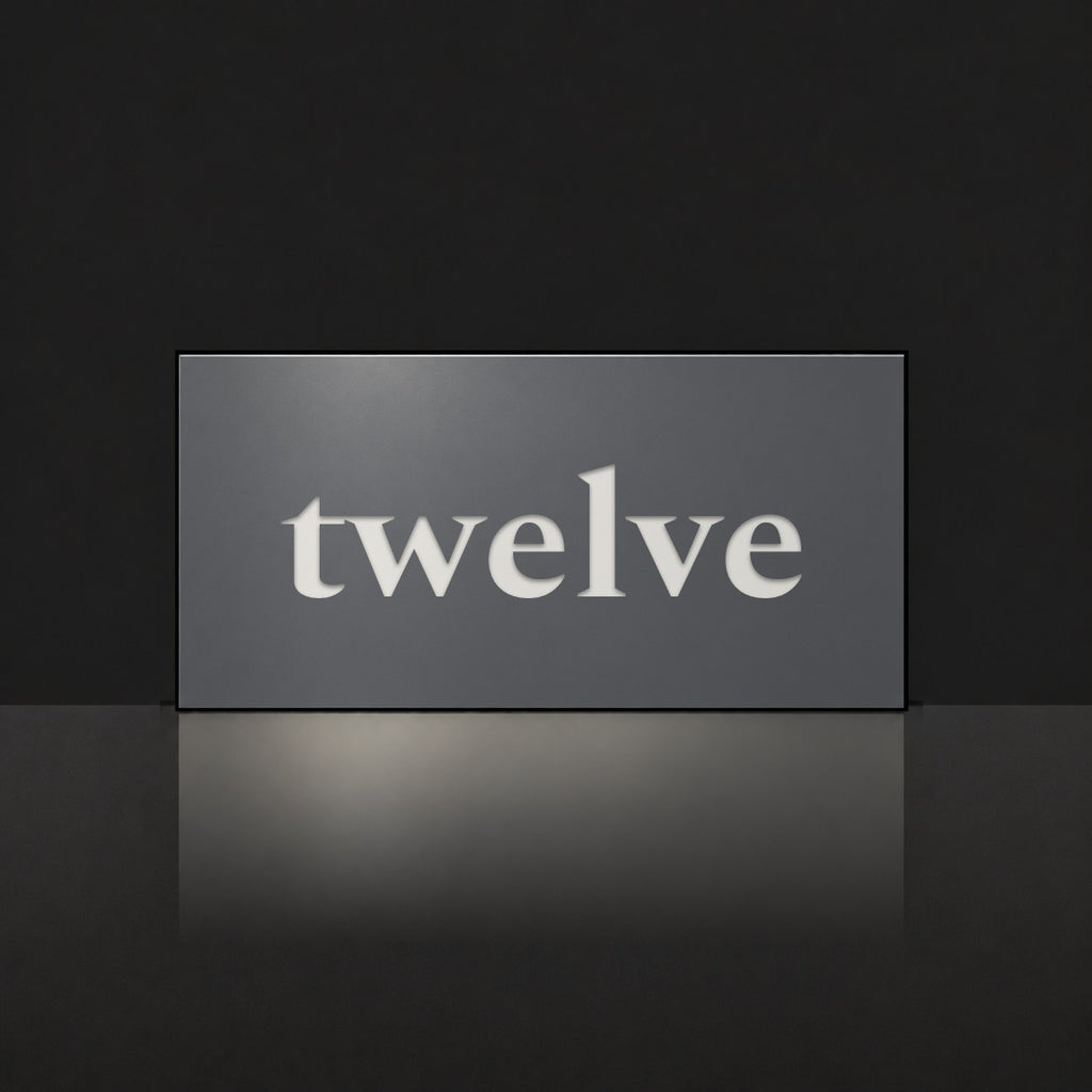 Matte charcoal house number sign, The Montville, with the number spelled out as twelve in white lettering.