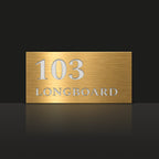 Brushed gold house number and street name sign with a brushed metal look, The Peregian, reading 103 Longboard in white lettering.