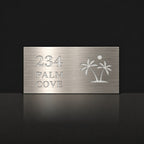 Brushed silver house number and street name sign with a brushed metal look, The Yaroomba, reading 234 Palm Cove in white lettering, with palm trees and a sun.