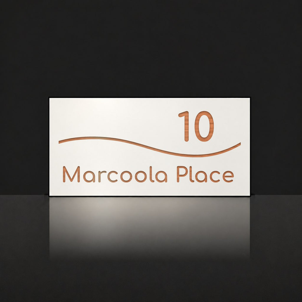 Brushed copper house number and street name sign with a brushed metal look, The Bokarina, white face reading 10 Marcoola Place in copper lettering, with a wave line.
