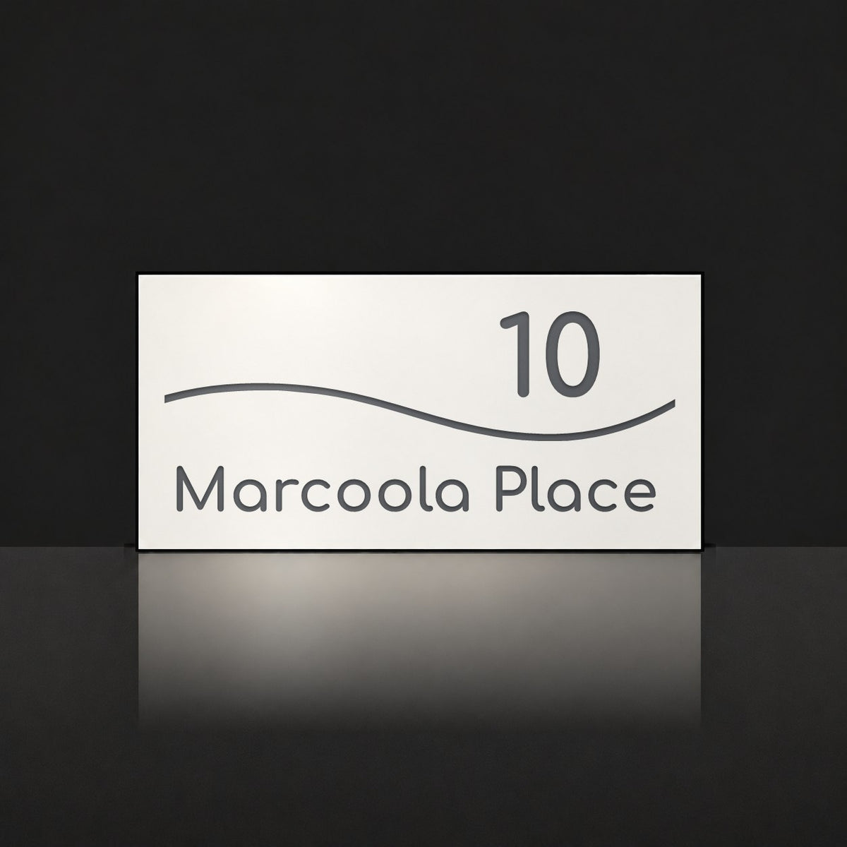 Matte white house number and street name sign, The Bokarina, reading 10 Marcoola Place in charcoal lettering, with a wave line.