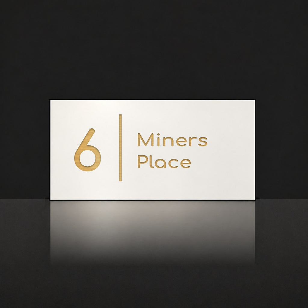 Brushed gold house number and street name sign with a brushed metal look, The Coolum, white face reading 6 Miners Place in gold lettering, with a dividing line.