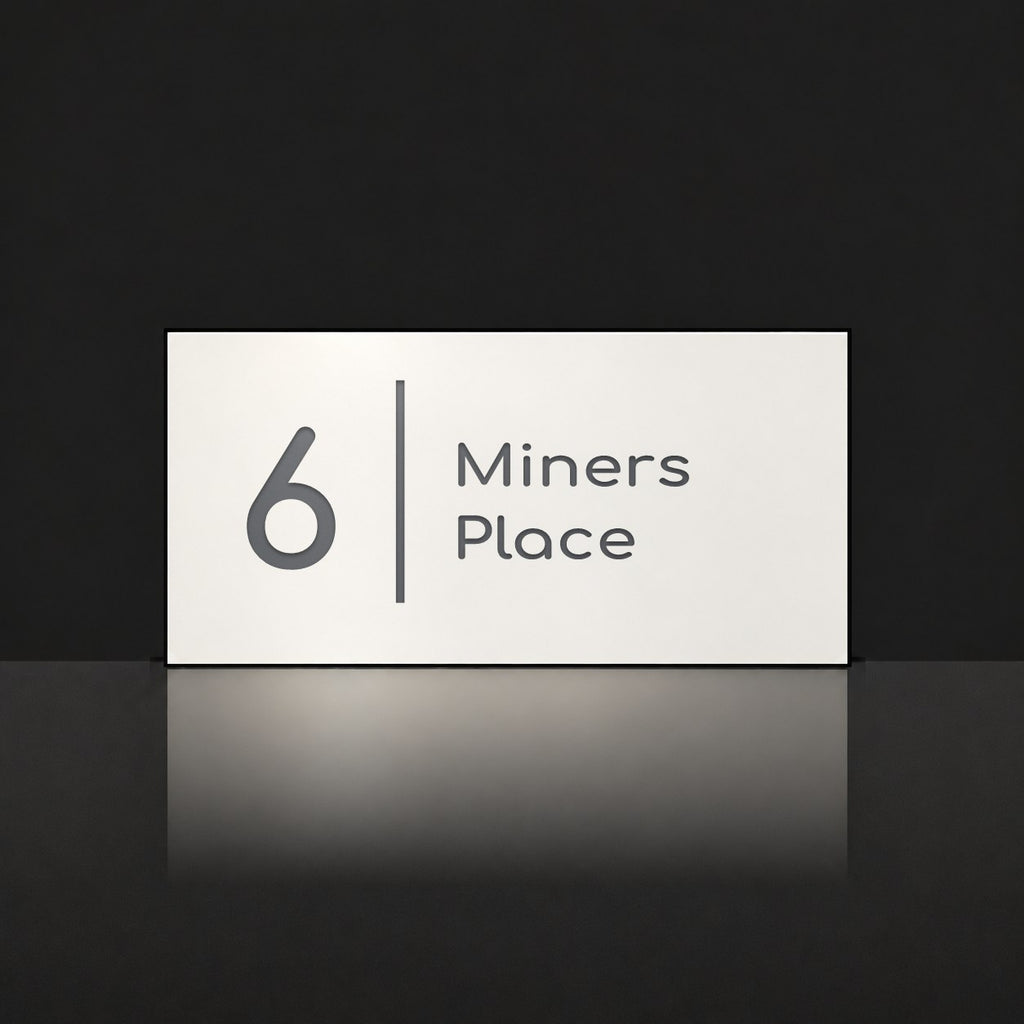 Matte white house number and street name sign, The Coolum, reading 6 Miners Place in charcoal lettering, with a dividing line.