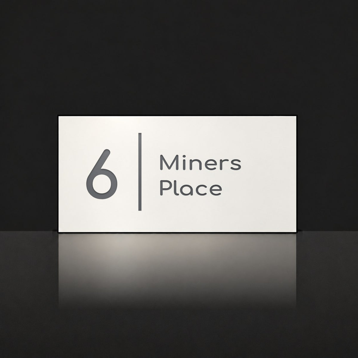 Matte white house number and street name sign, The Coolum, reading 6 Miners Place in charcoal lettering, with a dividing line.