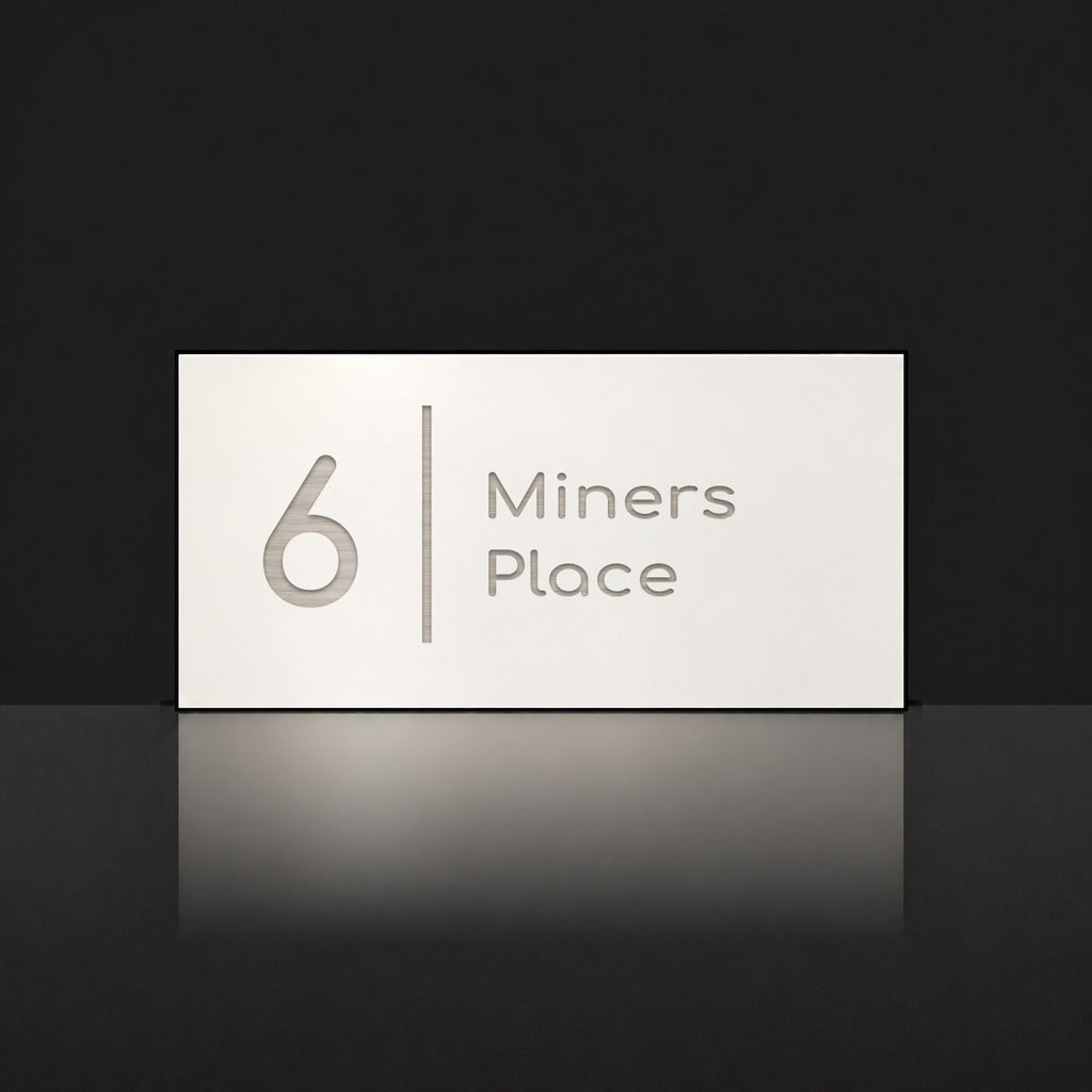 Brushed silver house number and street name sign with a brushed metal look, The Coolum, white face reading 6 Miners Place in silver lettering, with a dividing line.