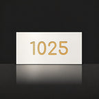 Brushed gold house number sign with a brushed metal look, The Kawana, white face with the number 1025 in gold lettering.