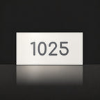 Matte white house number sign, The Kawana, with the number 1025 in charcoal lettering.