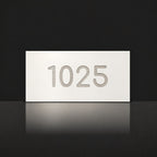 Brushed silver house number sign with a brushed metal look, The Kawana, white face with the number 1025 in silver lettering.