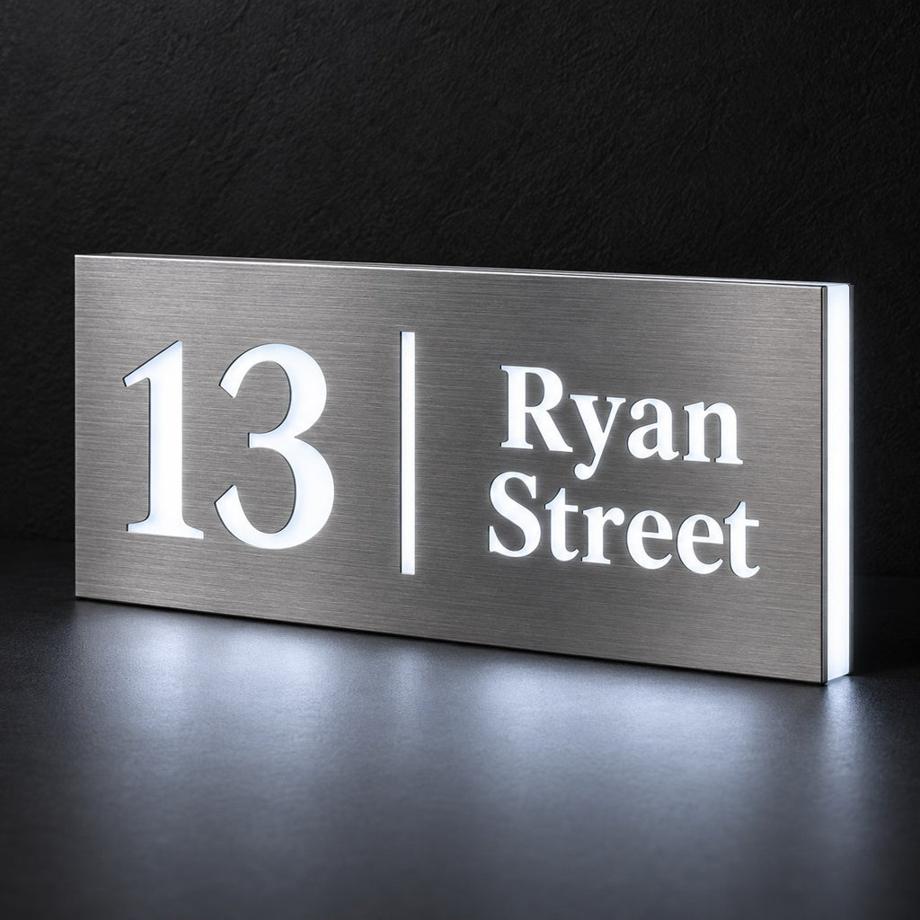Brushed silver illuminated house number and street name sign with a brushed metal look, The Coolum, 13 Ryan Street with the number, rule and street name lit from behind in cool white.