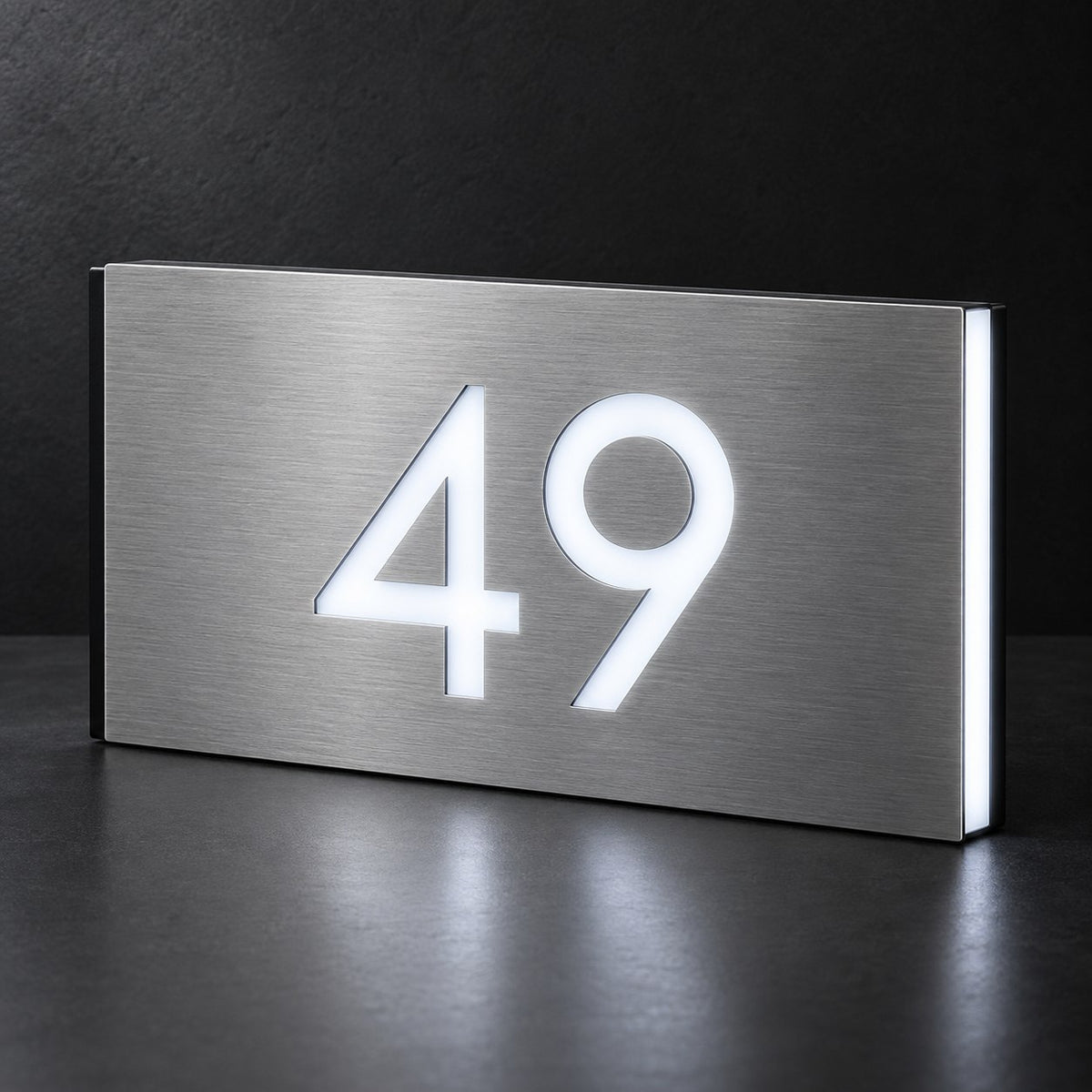 Brushed silver illuminated house number sign with a brushed metal look, The Kawana, showing the number 49 in bright white LED cutouts on a dark background.