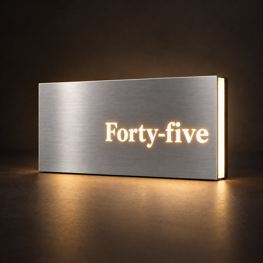 Brushed silver illuminated house number sign with a brushed metal look, The Montville, with the number spelled out as Forty-five, lit from behind in warm white.