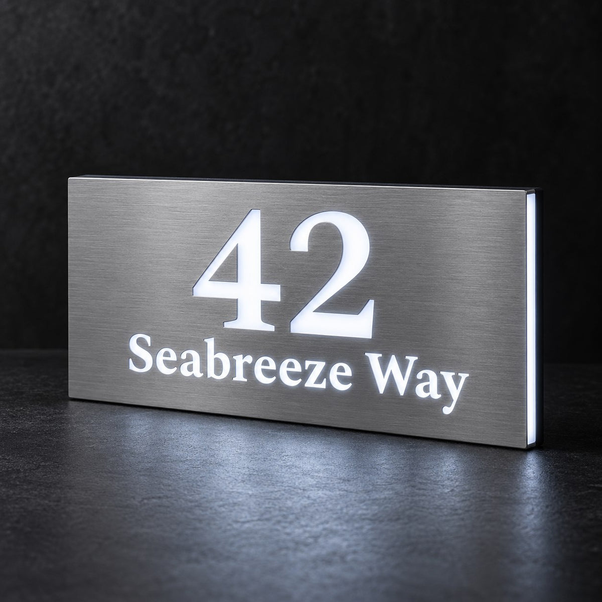 Brushed silver illuminated house number and street name sign with a brushed metal look, The Peregian, 42 Seabreeze Way cut through and lit from behind in cool white.