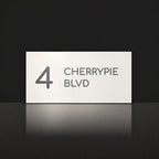 Matte white house number and street name sign, The Maleny, reading 4 Cherrypie Blvd in charcoal lettering.